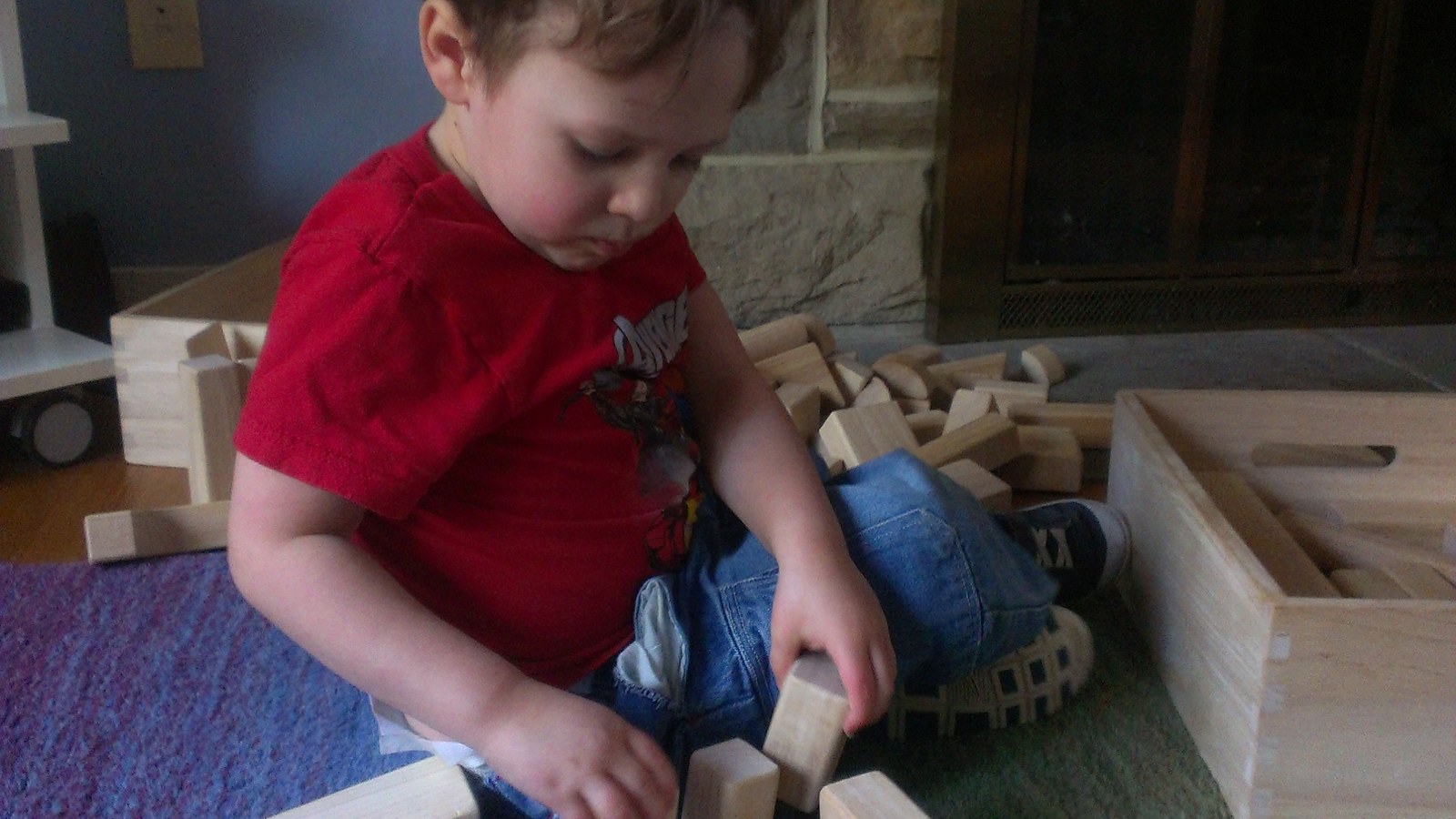 Enfant qui joue avec des blocs en bois posés sur un tapis