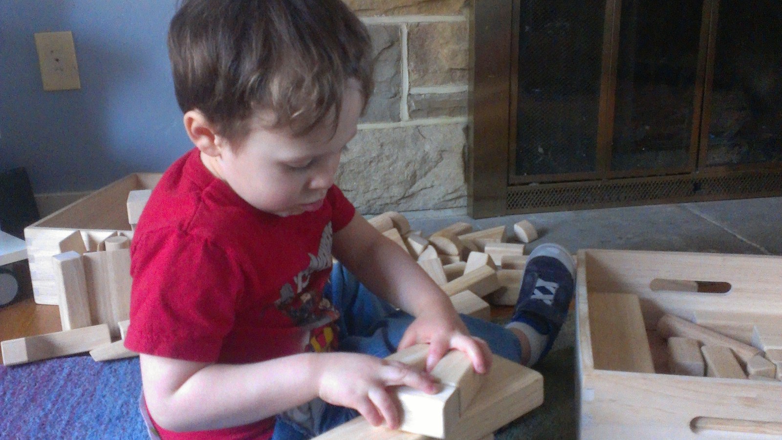 Enfant de deux ans qui joue avec des cubes en bois empilables sur un tapis