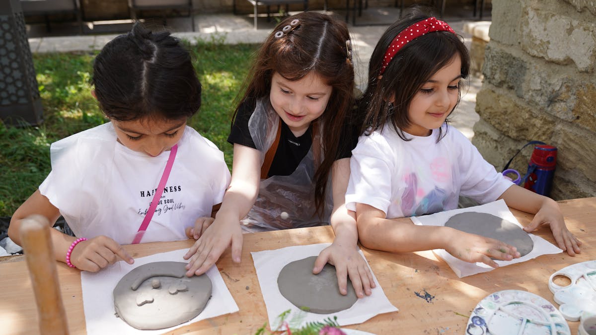 Trois enfants en train de modeler de la pâte lors d'un atelier créatif
