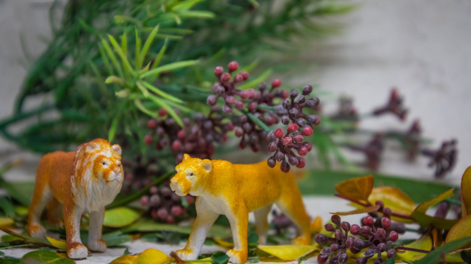 Figurines lion et lionne peintes à la main au milieu de feuillage