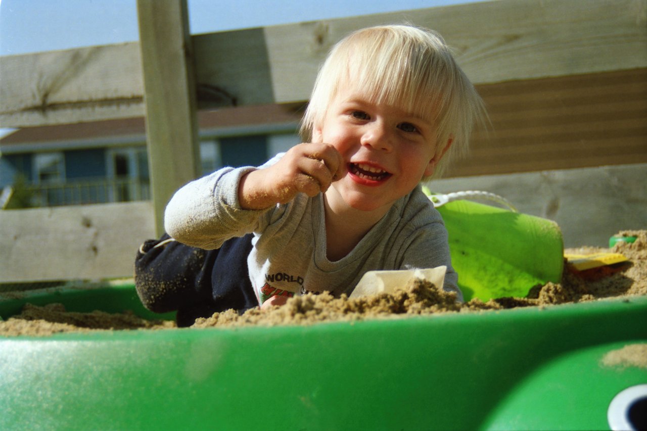Enfant souriant jouant dans le sable avec un seau et une pelle