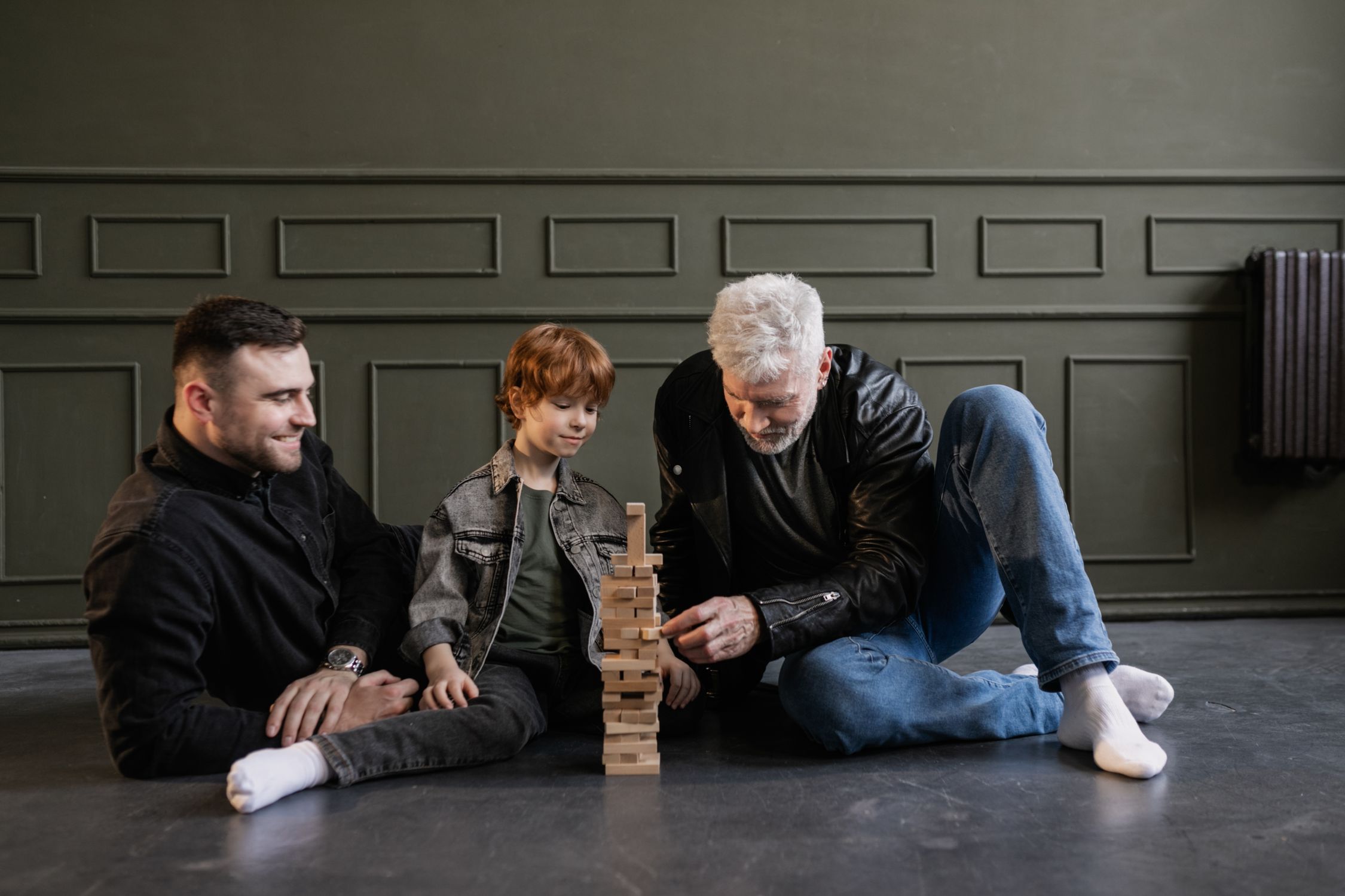Grand-père, père et enfant jouant à Jenga ensemble, trois générations