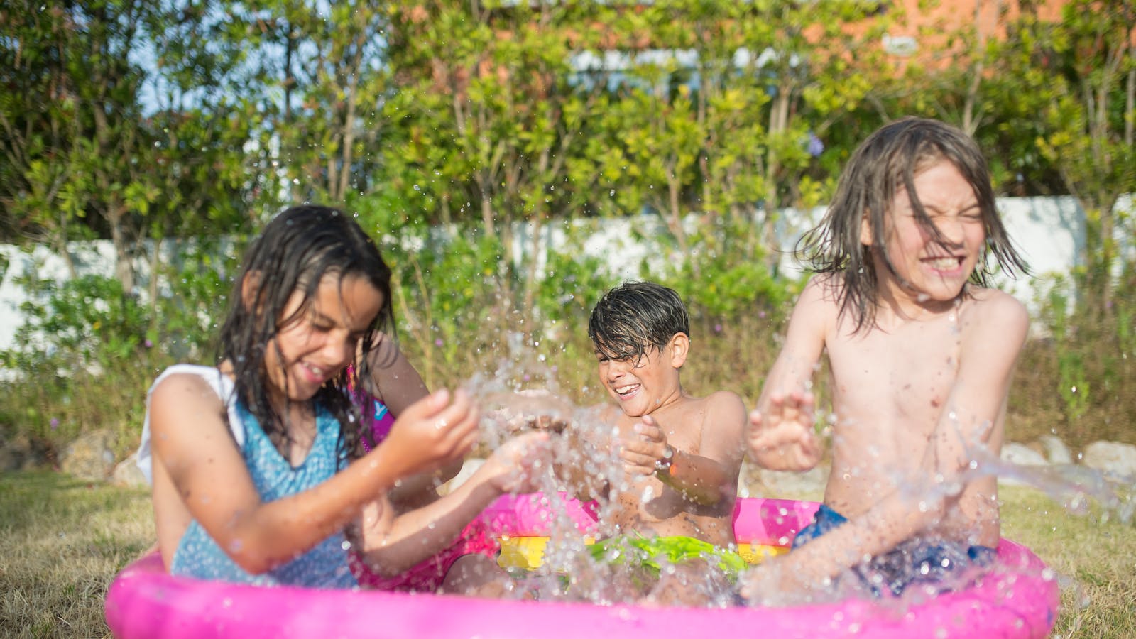 Trois enfants qui s'éclaboussent dans une piscine gonflable