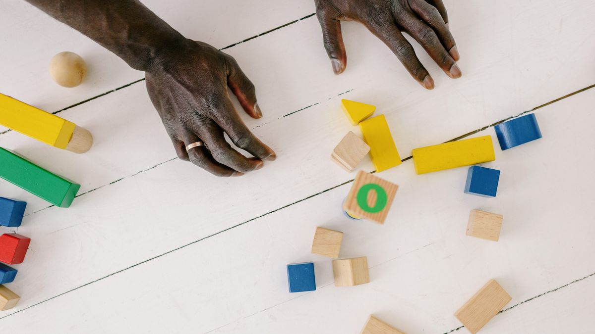 Jeux de construction en bois : blocs colorés Mains jouant avec des blocs en bois colorés sur une table blanche