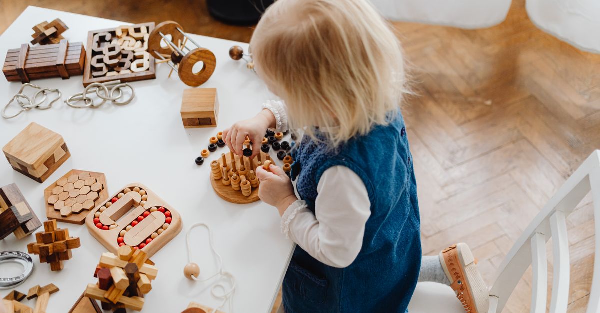 Jeune enfant concentré sur des jouets éducatifs en bois sur une table